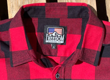 Load image into Gallery viewer, Close up of American Flag/Mountain Freedom Flannel logo neck tag on red and black buffalo check flannel. 
