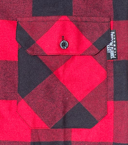 Close up of a red and black buffalo check flannel's chamfered pocket with Freedom Flannel star logo pinch hem tag. 